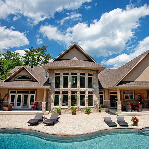 Rear view of home with plenty of windows overlooking a pool 